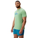 Man in a light green Canterbury Uglies CCC Logo T-Shirt by Canterbury (H225) with wave design and blue shorts, standing against a plain white background.