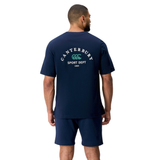 A man, facing away, wears the Canterbury Sport Dept. Logo T-Shirt by Canterbury in navy. The cotton blend tee features "Canterbury Sport Dept 1104" and a logo on the back, paired with shorts.