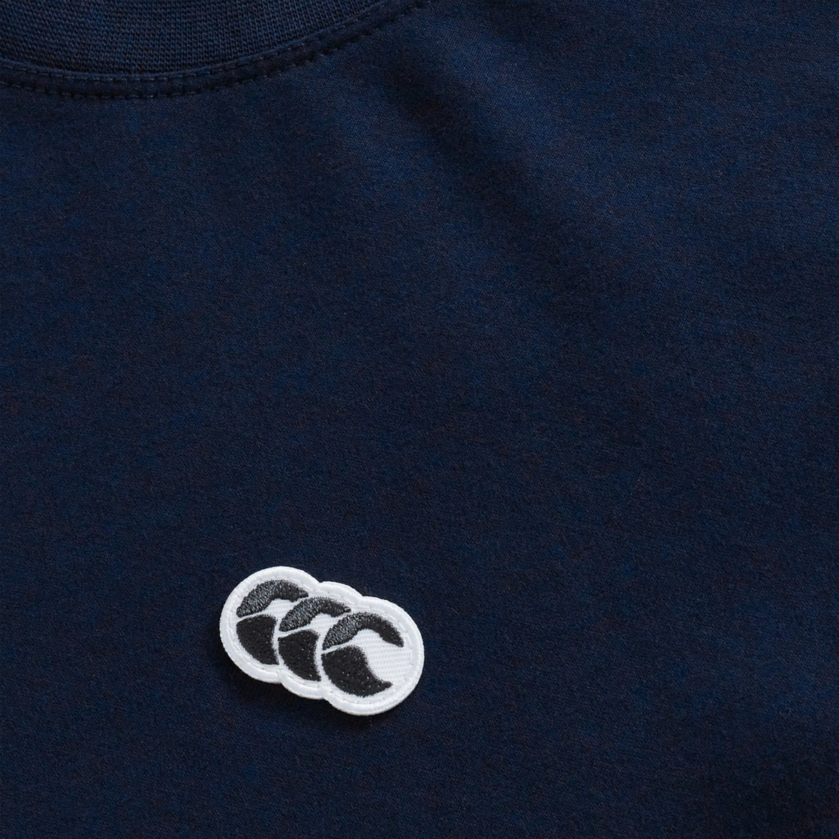 Close-up of the navy Sport Dept. Logo T-Shirt by Canterbury, made from an athletic cotton blend with a small embroidered white and black Canterbury logo featuring three overlapping shapes.