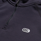 Close-up of the Canterbury Sport Dept. 1/4 Zip Sweater in a dark shade, showing a small white chest logo with three overlapping shapes.