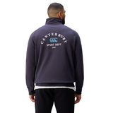 A man faces away, wearing the Canterbury Sport Dept. 1/4 Zip Sweater with "Sport Dept 1904" and a bold logo printed on the back.