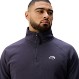 A man with short hair and a beard wears the dark Sport Dept. 1/4 Zip Sweater by Canterbury, featuring a white embroidered chest logo, standing against a plain white background.