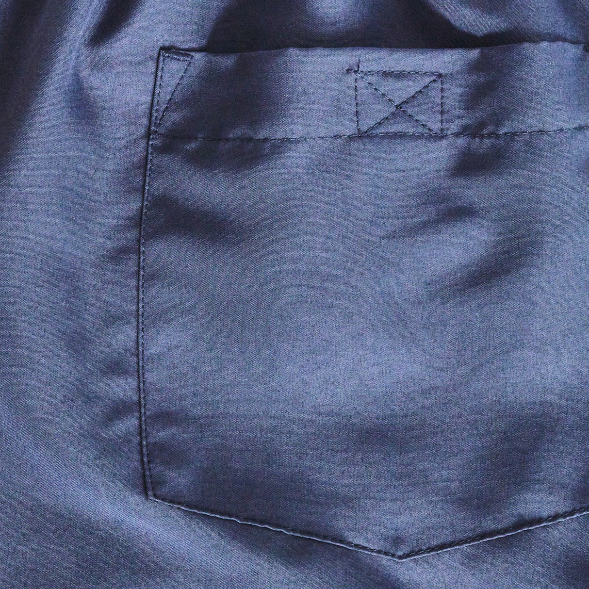 Close-up of blue satin fabric from the Canterbury Women's Fundamentals 3" Harletic Shorts, featuring a single rectangular pocket and sleek design.