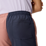 A woman wears Canterbury’s Fundamentals 3" Harletic Shorts, featuring color-blocking, an elastic waistband, and a back pocket, shown from the rear waist down.