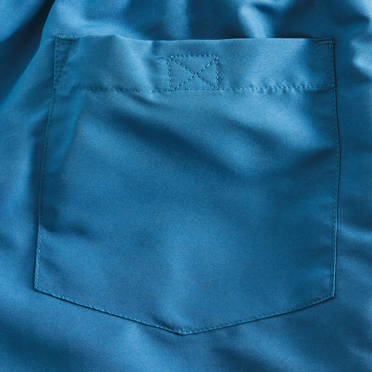 A close-up of a blue shirt’s chest pocket reveals fine stitching and smooth texture—mirroring the quality of Canterbury’s Women's Fundamentals 3" Harletic Shorts.
