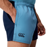 A person wearing Canterbury Fundamental Harlequin Drill 3" Shorts, featuring a visible logo and a hand in the pocket.