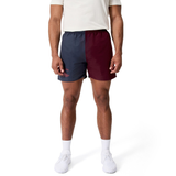 A person wearing a white shirt, Canterbury Fundamental Harletic 3" Shorts in navy and burgundy, and white sneakers stands against a plain white background.