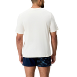 A man stands facing away, wearing a plain white Force CCC T-Shirt by Canterbury and navy blue patterned shorts, against a white background.