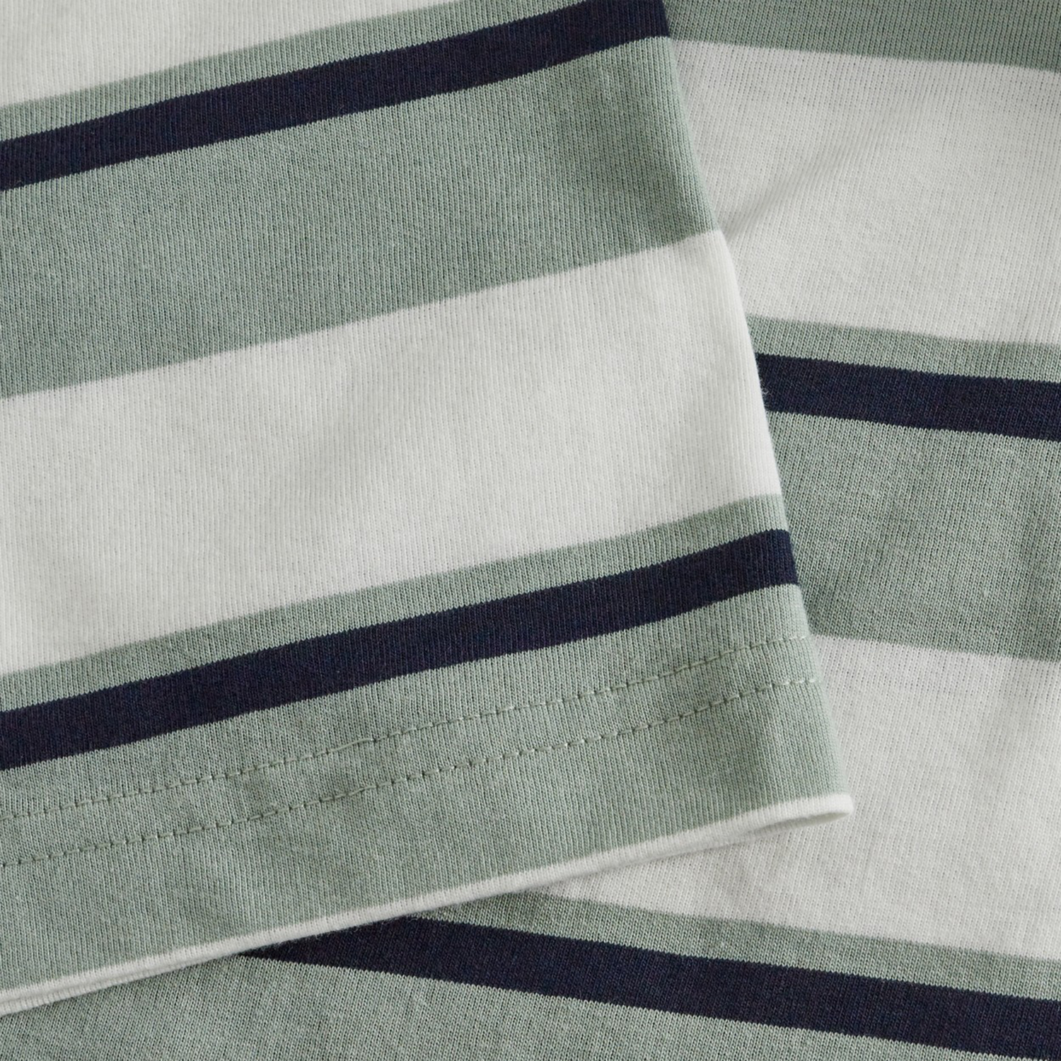 Close-up of two overlapping pieces of fabric with green, white, and dark blue stripes from the Fundamental Yarn Dye Stripe T-Shirt by Canterbury, featuring a rugby-inspired design.