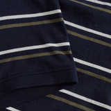 Close-up of the Fundamental Yarn Dye Stripe Polo by Canterbury, featuring navy blue fabric with horizontal white and olive green stripes, highlighting part of the sleeve and body.