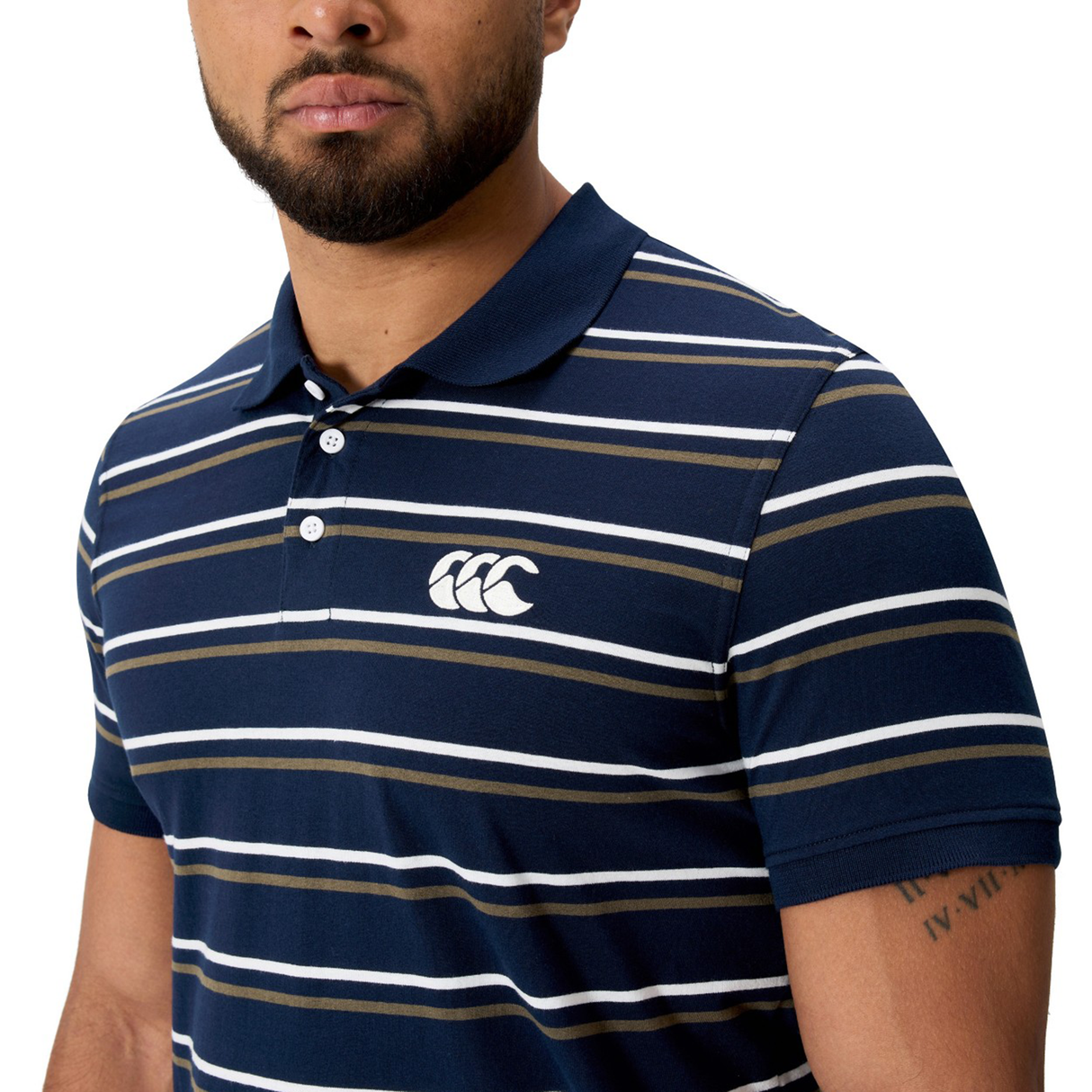 A man wearing the Canterbury Fundamental Yarn Dye Stripe Polo in navy, white, and beige, featuring a chest logo.
