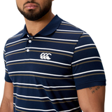 A man is wearing the Canterbury Yarn Dye Stripe Polo by Canterbury, featuring a navy blue base with horizontal white and brown stripes and a white logo on the chest.