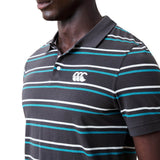 A man is shown from the shoulders down wearing the Canterbury Yarn Dye Stripe Polo by Canterbury, a dark collared shirt featuring yarn-dyed stripes and a white logo on the chest, set against a white background.