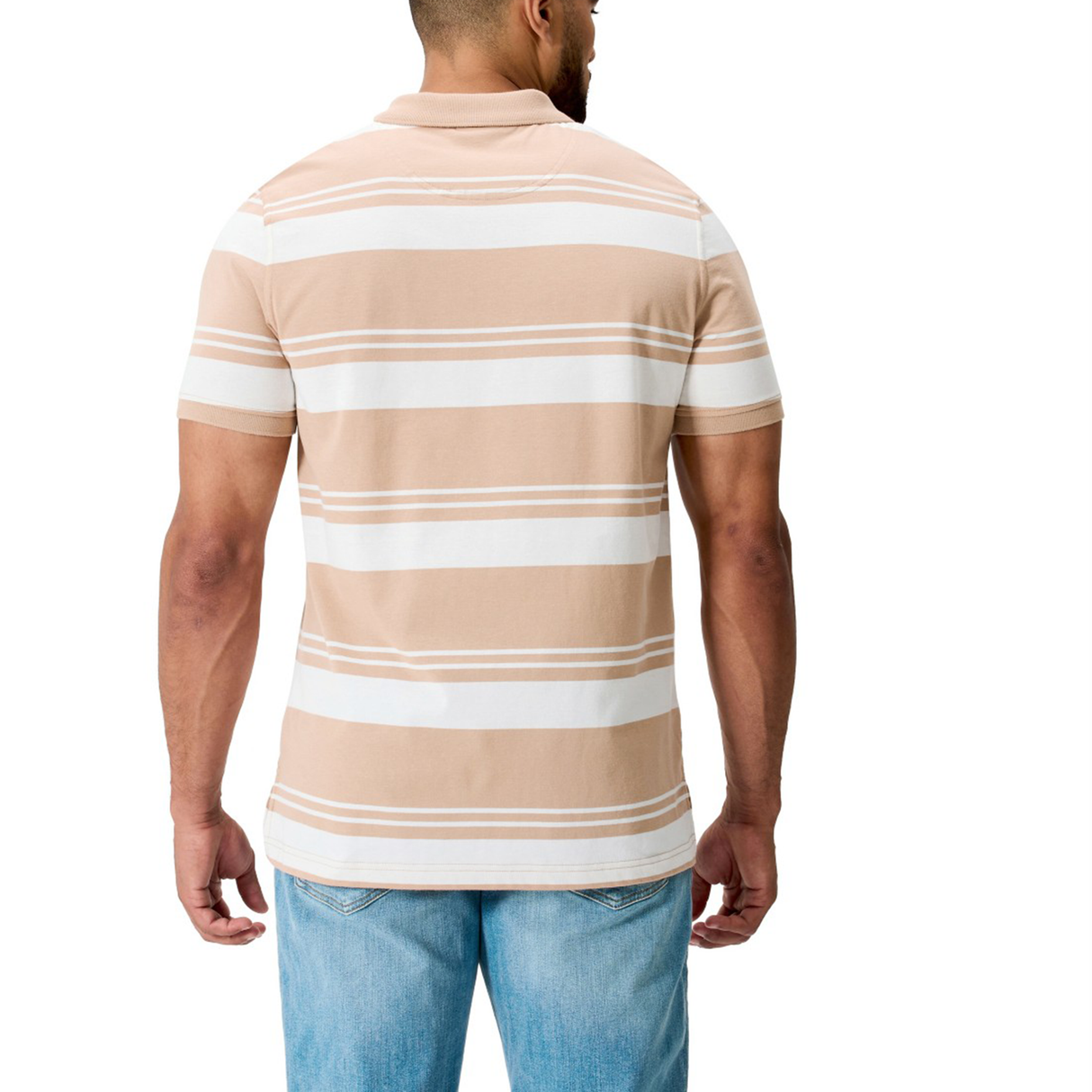A man is shown from the back wearing Canterbury's Fundamental Engineered Stripe Polo, featuring beige and white rugby-inspired stripes, paired with light blue jeans.