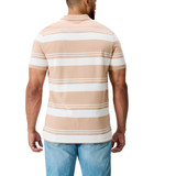 A man is shown from the back wearing Canterbury's Fundamental Engineered Stripe Polo, featuring beige and white rugby-inspired stripes, paired with light blue jeans.