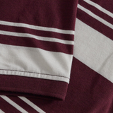 Close-up of the sleeve hem overlapping the body on the Canterbury Fundamental Engineered Stripe Polo, featuring maroon and white stripes in this classic rugby style.