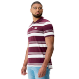 A man wearing the Canterbury Fundamental Engineered Stripe Polo in maroon and white with a chest logo, paired with light blue jeans, stands against a white background.
