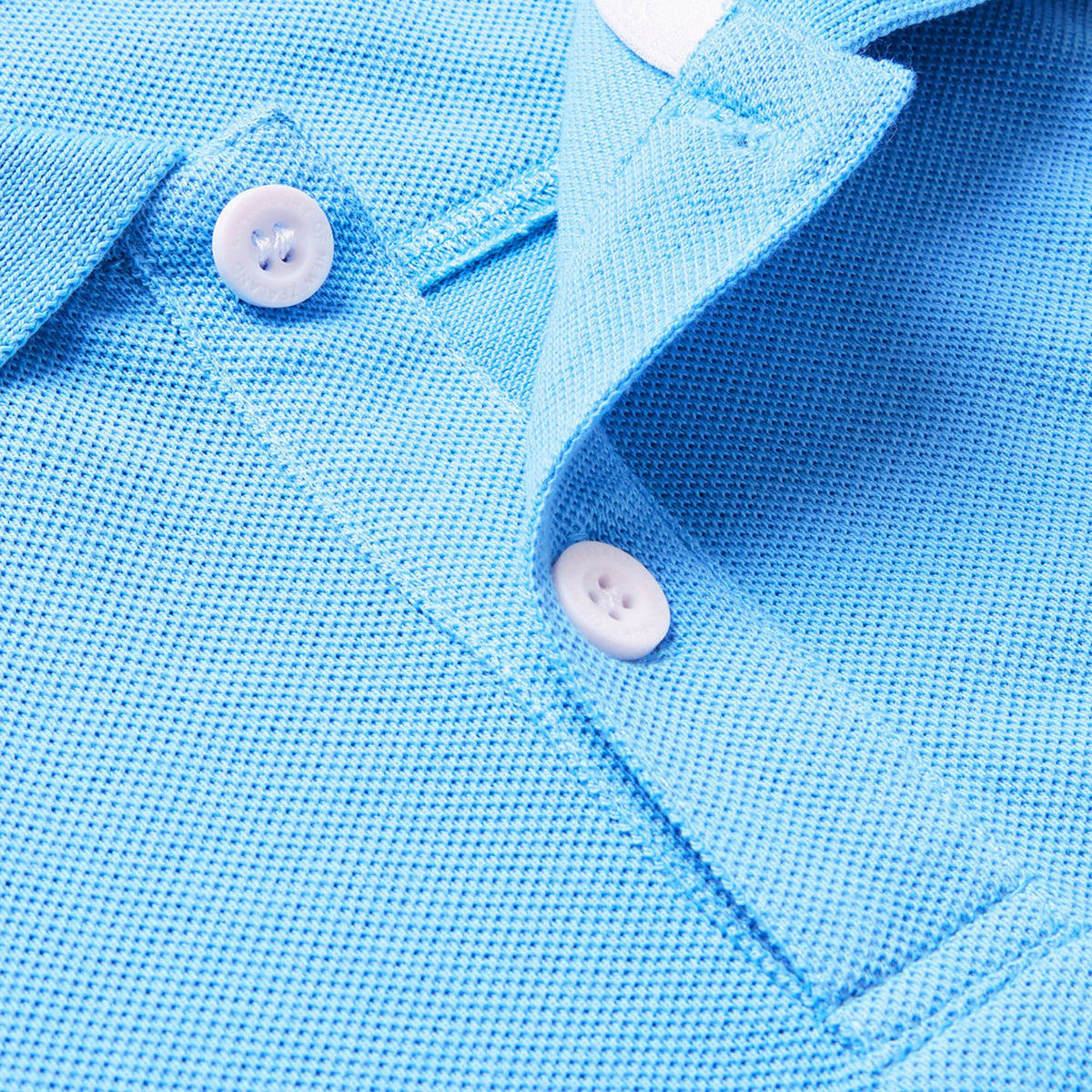 A close-up of the Canterbury Solid Dye Polo by Canterbury in light blue showcases its textured fabric, two white buttons, and a portion of the collar.
