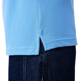 Close-up of the hem of the Canterbury Solid Dye Polo by Canterbury in light blue, featuring a small side slit, worn over dark blue denim jeans.