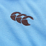 Close-up of a blue textured fabric from the Canterbury Solid Dye Polo, featuring a black embroidered Canterbury logo with three overlapping curved shapes.