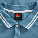 Close-up of the Canterbury Fundamental Solid Dye Polo in blue, featuring a white-striped collar, white button, and black size L label—highlighting its classic rugby-inspired style.