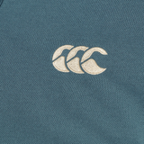 Close-up of a teal fabric from the Canterbury Solid Dye Polo, featuring an embroidered white Canterbury logo with three overlapping curved shapes, capturing the athletic style of this classic polo.