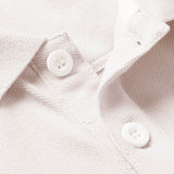 Close-up of the Canterbury Solid Dye Polo by Canterbury in white, highlighting the textured fabric, precise stitching, and two white buttons.