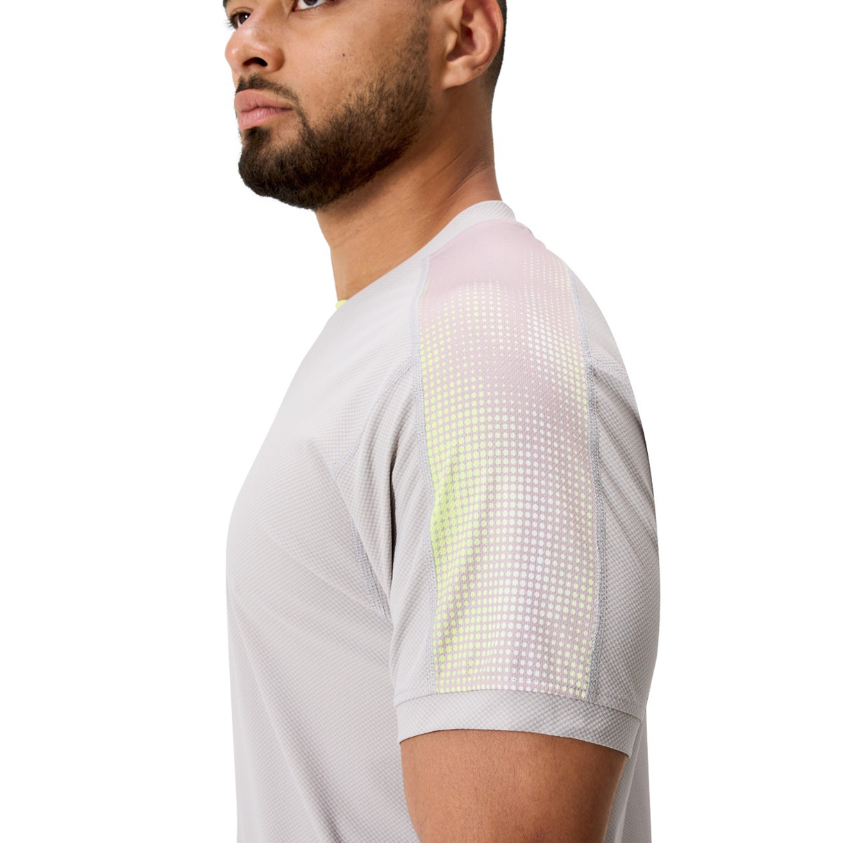 A man in a side profile wears the Canterbury Tempo+ Drill Top, a light gray performance training top with pink and yellow dotted shoulder accents.
