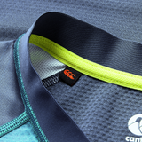 Close-up of the Ireland 26/27 Summer Tour "Baltic" Training Test Jersey by Canterbury in blue with yellow-green trim, mesh fabric, and a black tag with an orange logo—perfect for supporting your team this summer.