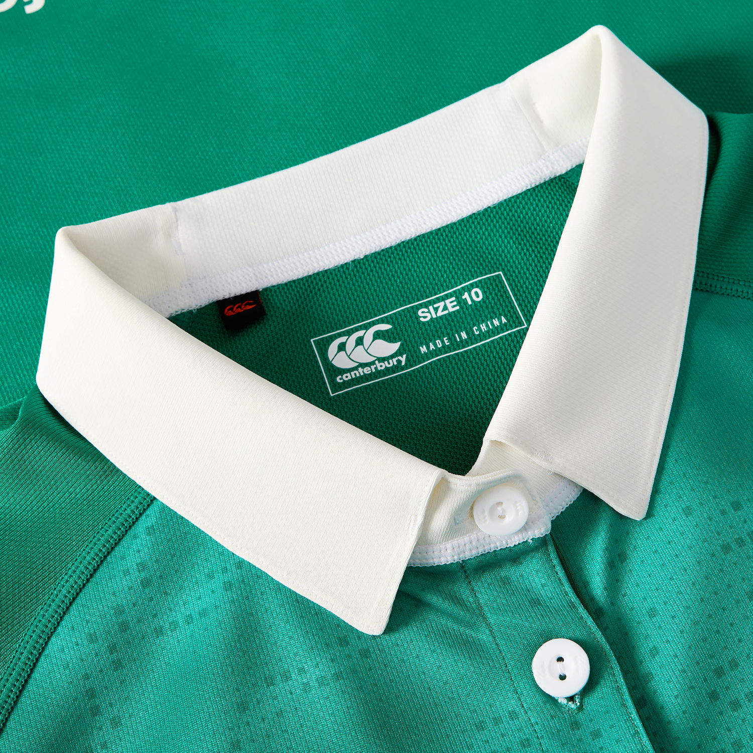 Close-up of the Canterbury Women's Ireland WIRFU 25/26 Pro Home Jersey in green, featuring a white collar with buttons and a visible size 10 label plus "Made in China" text inside the neckline.