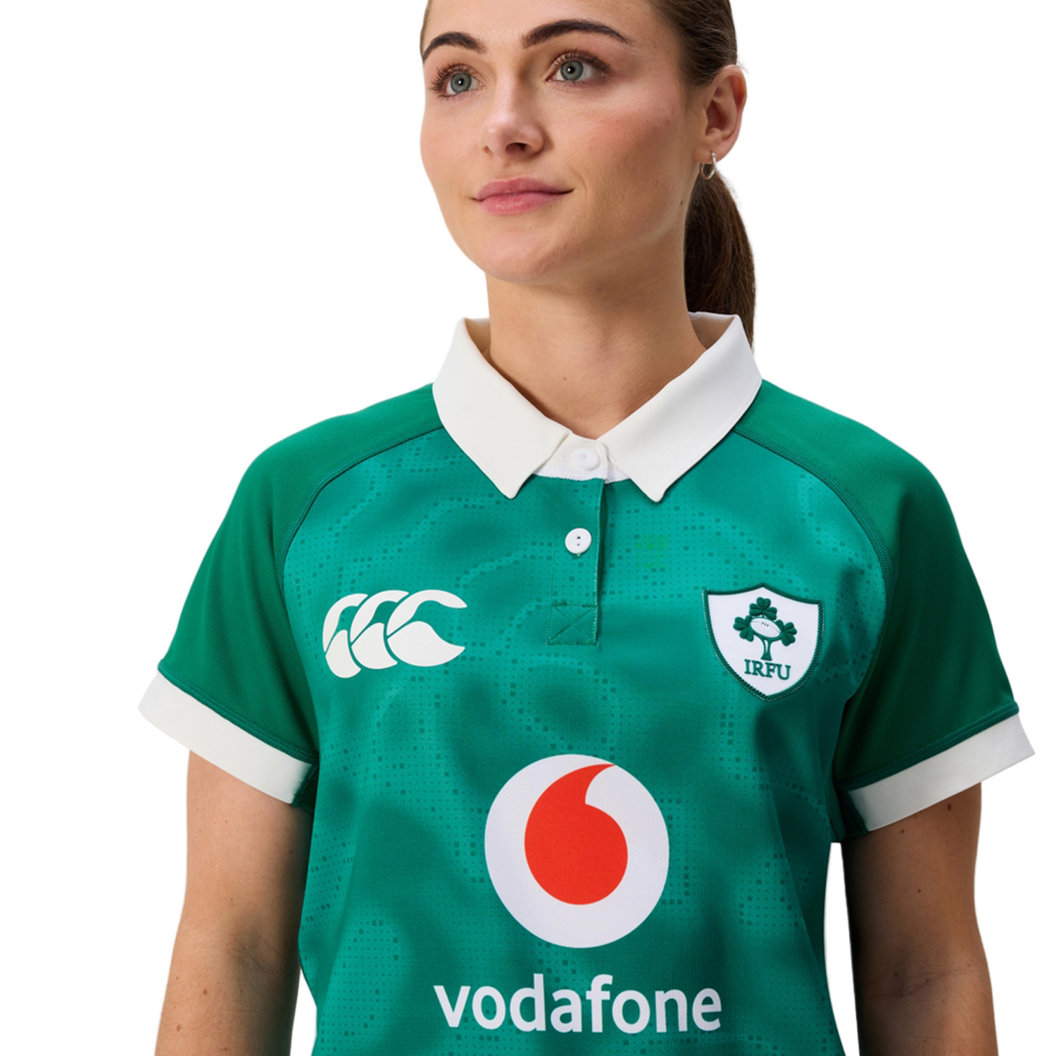 A woman stands against a plain background wearing the Women's Ireland 25/26 Home Pro Jersey by Canterbury—a green IRFU jersey with Canterbury and Vodafone logos.