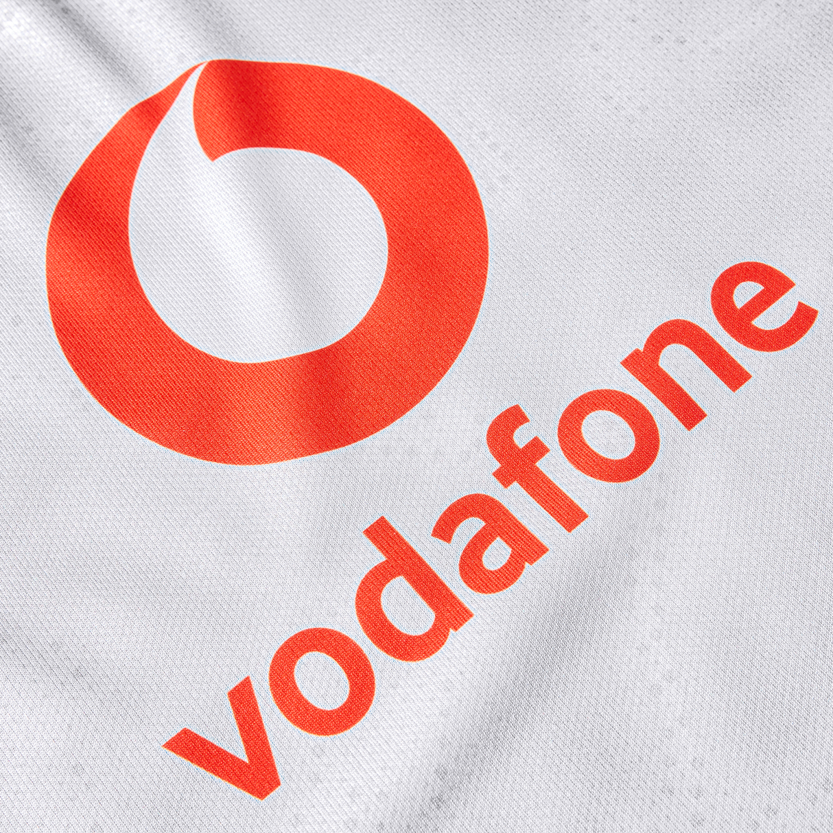 Close-up of a white fabric from the Women's Ireland 25/26 Alternate Pro Jersey by Canterbury, featuring the Vodafone logo and red "vodafone" text printed diagonally.
