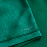 Close-up of green textured fabric from the Ireland 25/26 Home Pro Jersey by Canterbury, featuring "VAPODRI" printed in silver near the hem.
