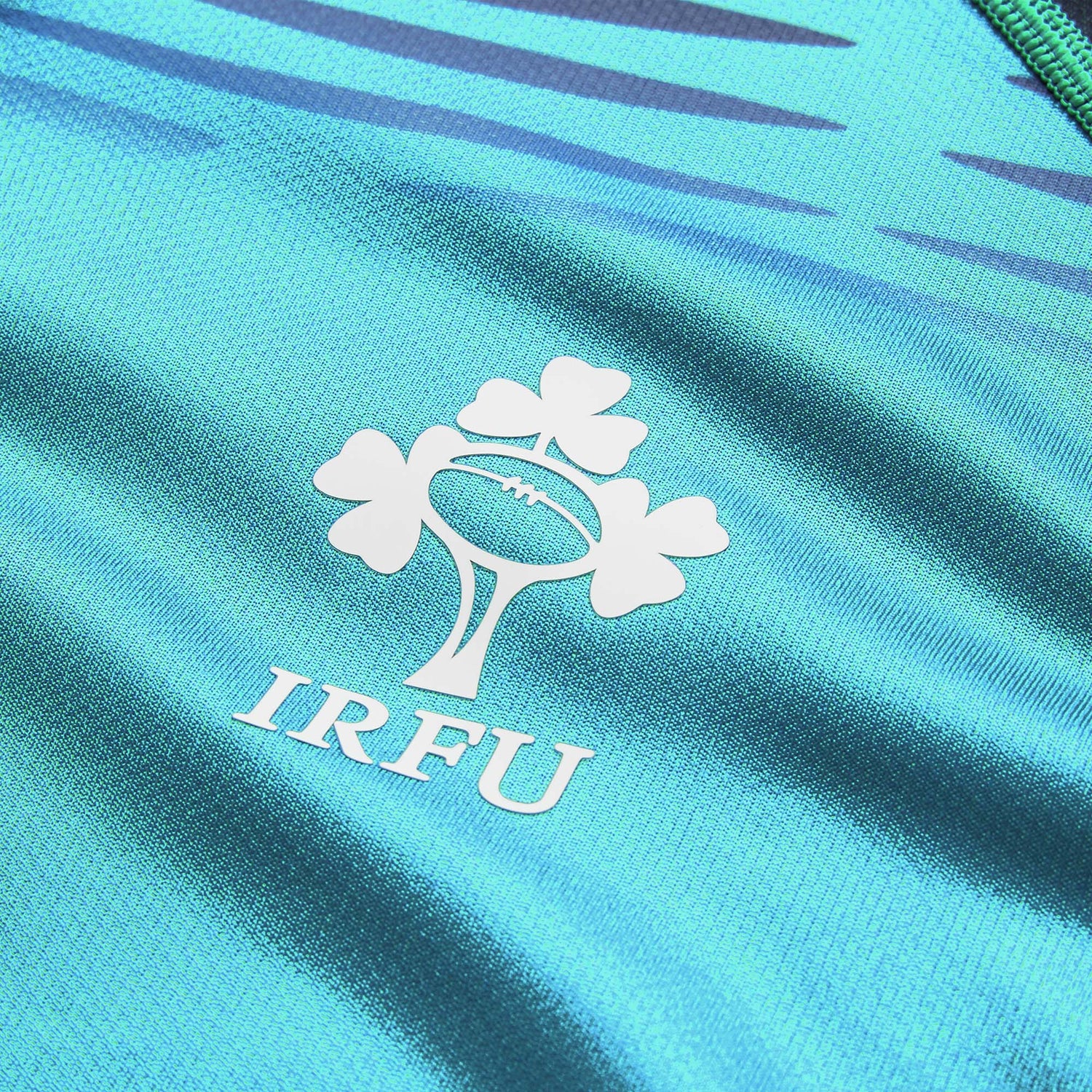 Close-up of the Ireland 26 Pre Game Pro Jersey by Canterbury, a turquoise moisture-wicking sports jersey featuring the white IRFU logo with a shamrock and rugby ball design.