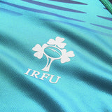 Close-up of the Ireland 26 Pre Game Pro Jersey by Canterbury, a turquoise moisture-wicking sports jersey featuring the white IRFU logo with a shamrock and rugby ball design.