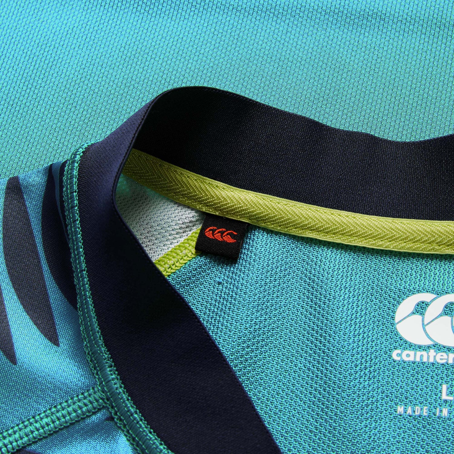 Close-up of the neckline of the Ireland 26 Pre Game Pro Jersey by Canterbury featuring visible Canterbury logos, lime green trim, and textured, moisture-wicking fabric.