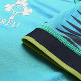 Close-up of the Ireland 26 Pre Game Pro Jersey by Canterbury, showcasing its turquoise color with black and green trim, a logo featuring a shamrock and rugby ball alongside the letters “IRFU.” This Canterbury jersey is designed as a moisture-wicking sports top for optimal comfort on or off the field.