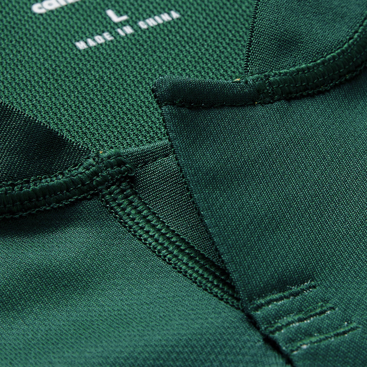 Close-up of the collar on a green Ireland 26 Training Pro Jersey by Canterbury, highlighting detailed stitching, fabric texture, and a visible tag marked size L and “Made in China.” The meticulous craftsmanship is characteristic of Canterbury’s premium quality, often associated with their iconic Ireland Rugby Jersey designs.