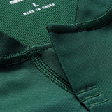 Close-up of the collar on a green Ireland 26 Training Pro Jersey by Canterbury, highlighting detailed stitching, fabric texture, and a visible tag marked size L and “Made in China.” The meticulous craftsmanship is characteristic of Canterbury’s premium quality, often associated with their iconic Ireland Rugby Jersey designs.