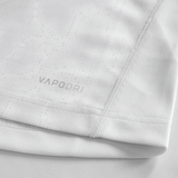 Close-up of the Youth Ireland 25/26 Alternate Pro Jersey by Canterbury in light grey, showing "VAPODRI" near the hem, detailed stitching, and textured fabric—an ideal pick for young rugby fans.