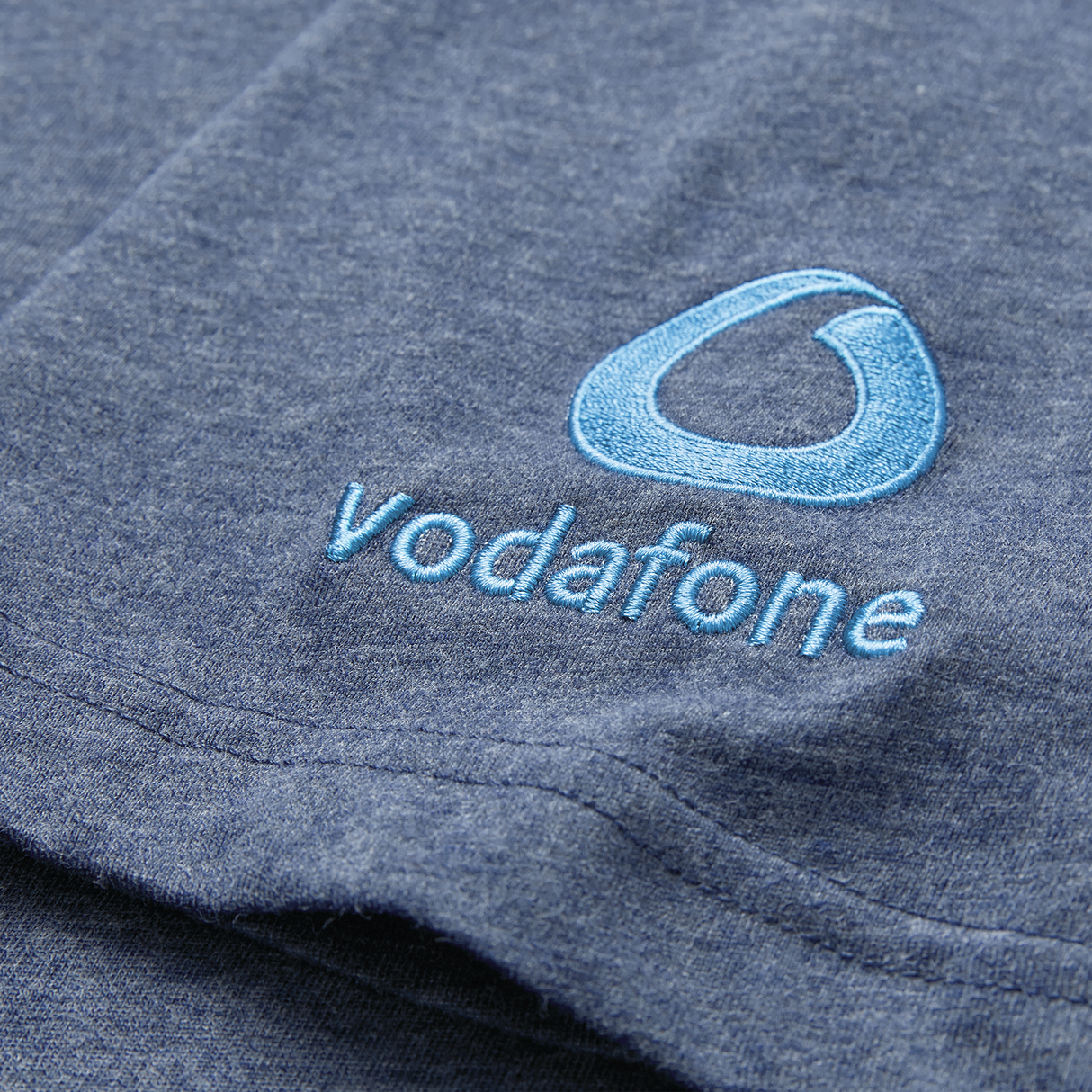A close-up of the Ireland 26/27 Summer Tour Team Cotton T-Shirt by Canterbury in blue, featuring an embroidered Vodafone logo and light blue text—ideal for fans supporting the summer tour.