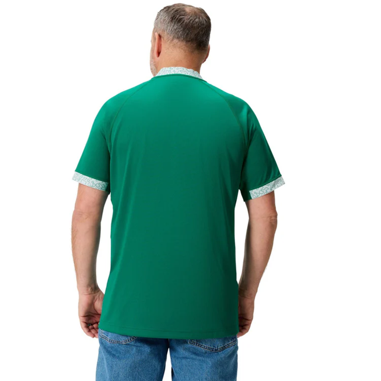 A man with gray hair and a beard is seen from behind wearing the Canterbury Ireland WRWC25 Replica Home Jersey with patterned trim and blue jeans, set against a white background.