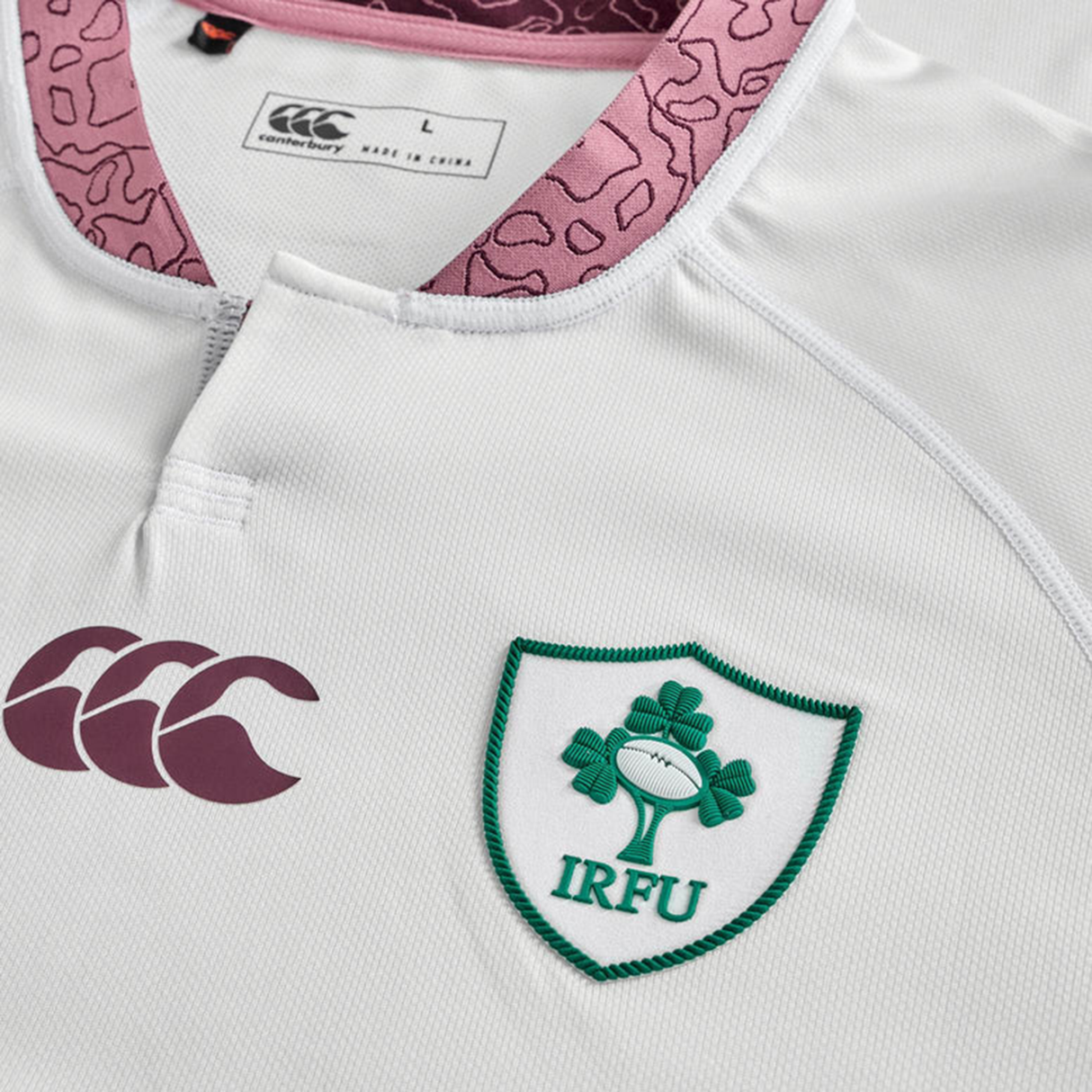 A close-up of the Ireland WRWC25 Replica Alternate Jersey by Canterbury highlights the Canterbury logo, IRFU crest with shamrock and ball, and a pink-patterned collar—making it a standout rugby jersey for World Cup 2025.