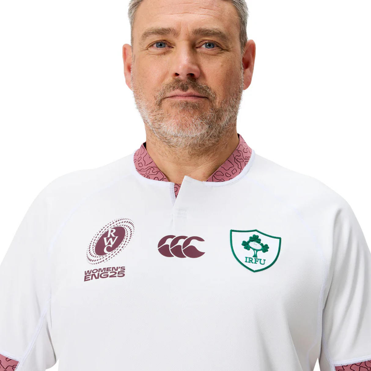A man with a gray beard wears the Ireland WRWC25 Replica Alternate Jersey by Canterbury, a white sports top featuring the IRFU shamrock badge, Canterbury branding, and the Rugby World Cup 2025 Women's England emblem.