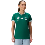 A woman wears the Canterbury Women's Ireland WRWC25 Replica Home Jersey with sponsor logos and light blue jeans, facing slightly left against a plain white background.