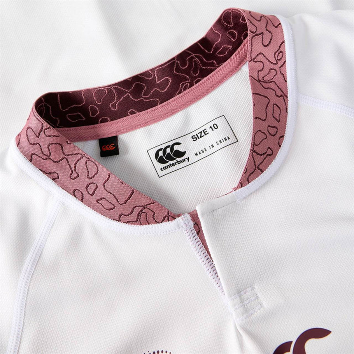 Close-up of the Women's Ireland WRWC25 Replica Alternate Jersey by Canterbury, white with a maroon patterned collar, featuring a "SIZE 10" and "MADE IN CHINA" brand tag.