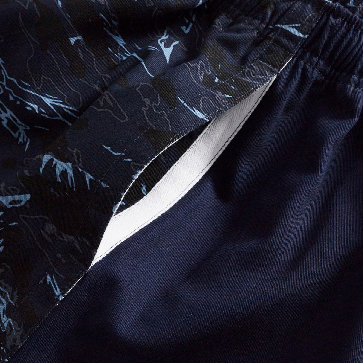 Close-up of Canterbury’s Force Harlequin Drill Shorts in navy blue, showing a white inner lining, open side pocket, and a black and blue abstract-patterned waistband.