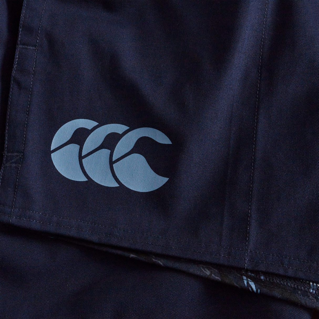 A close-up of navy blue fabric from Canterbury Force Harlequin Drill Shorts, displaying the light grey CCC logo.