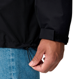 A person in blue jeans uses one hand to tighten the hem drawstring of a Canterbury Ireland 25/26 Water Resistant Insulated Jacket.