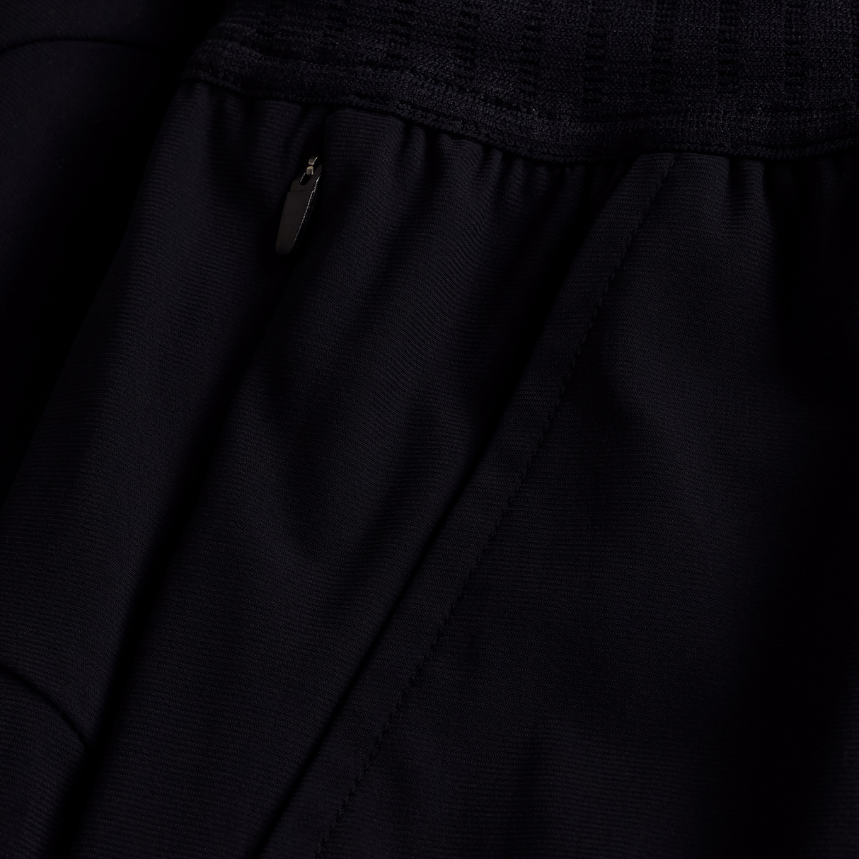 Close-up of the black Ireland 25/26 Gym Training Short by Canterbury, showcasing a zippered pocket with metallic pull and detailed stitched seams.